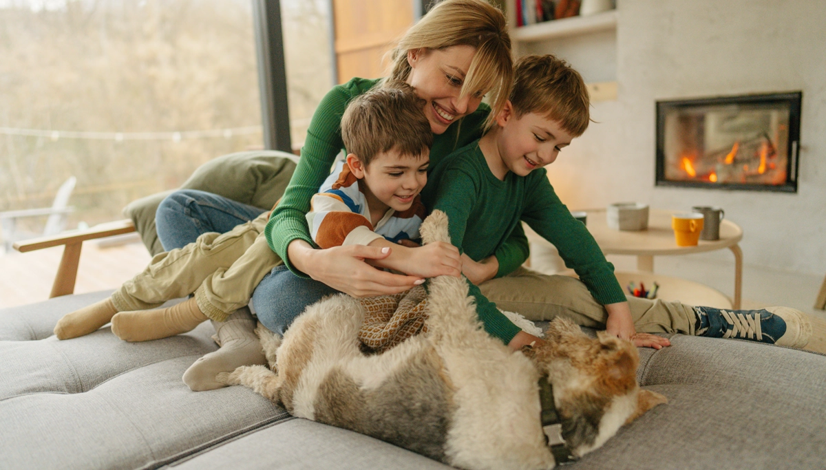 A mother and two children playing with a dog