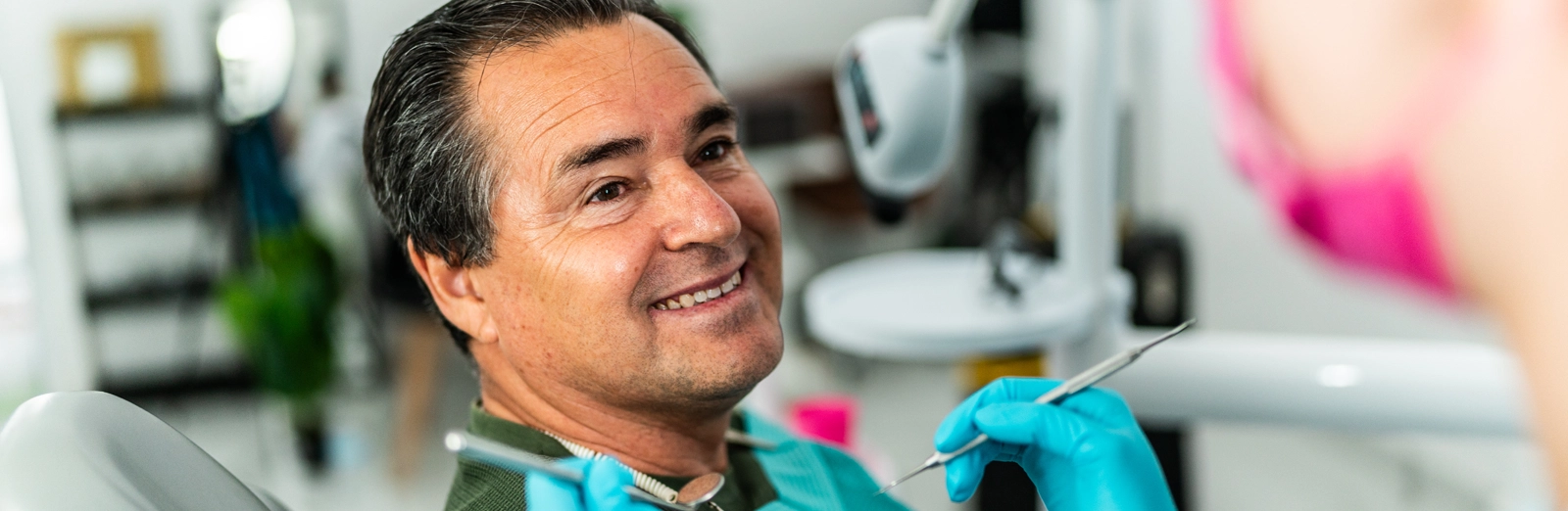 A smiling man in a dentist chair waiting for his dentist to start his treatment