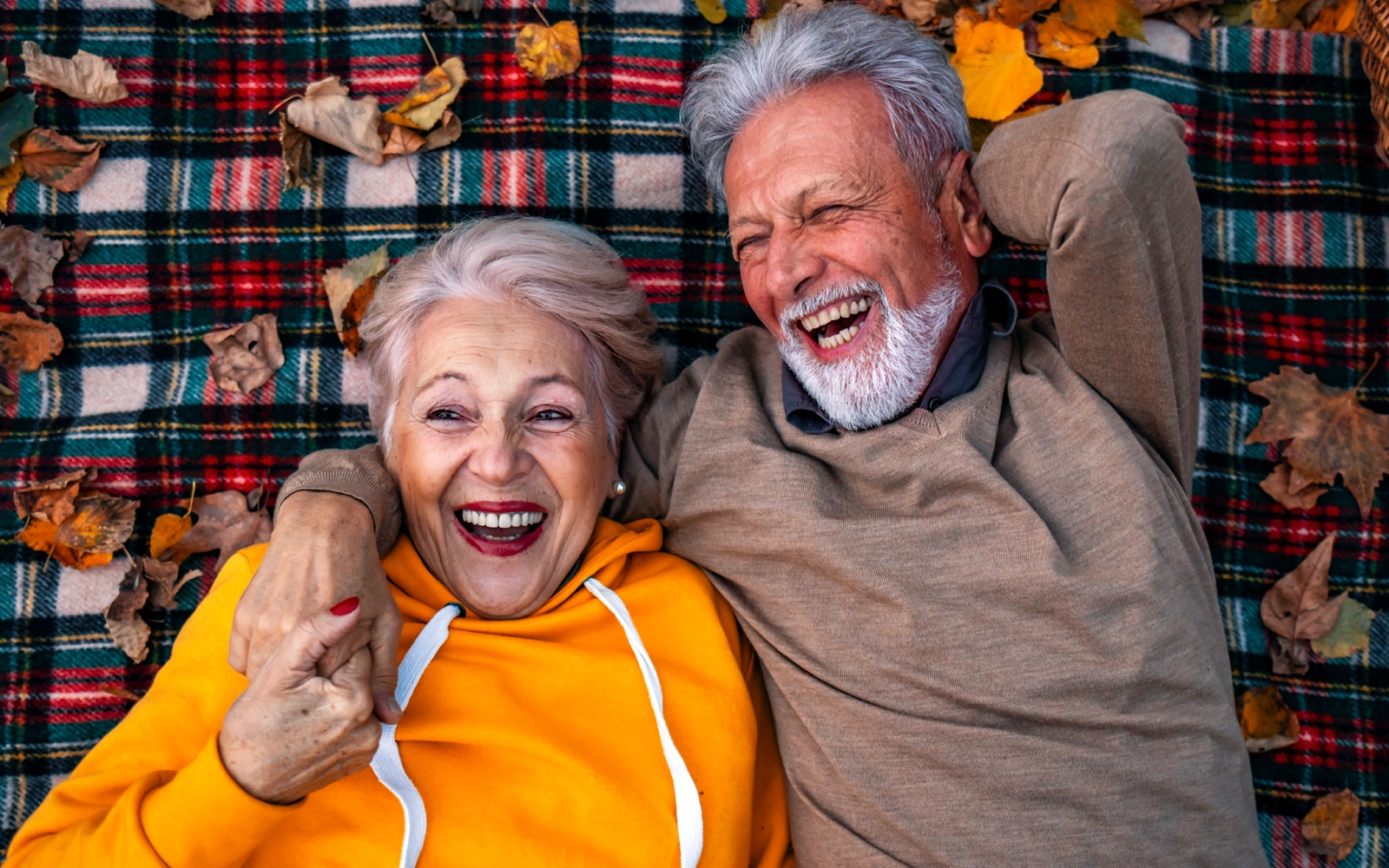older_couple_laying_on_blanket_laughing_1600x1000.webp