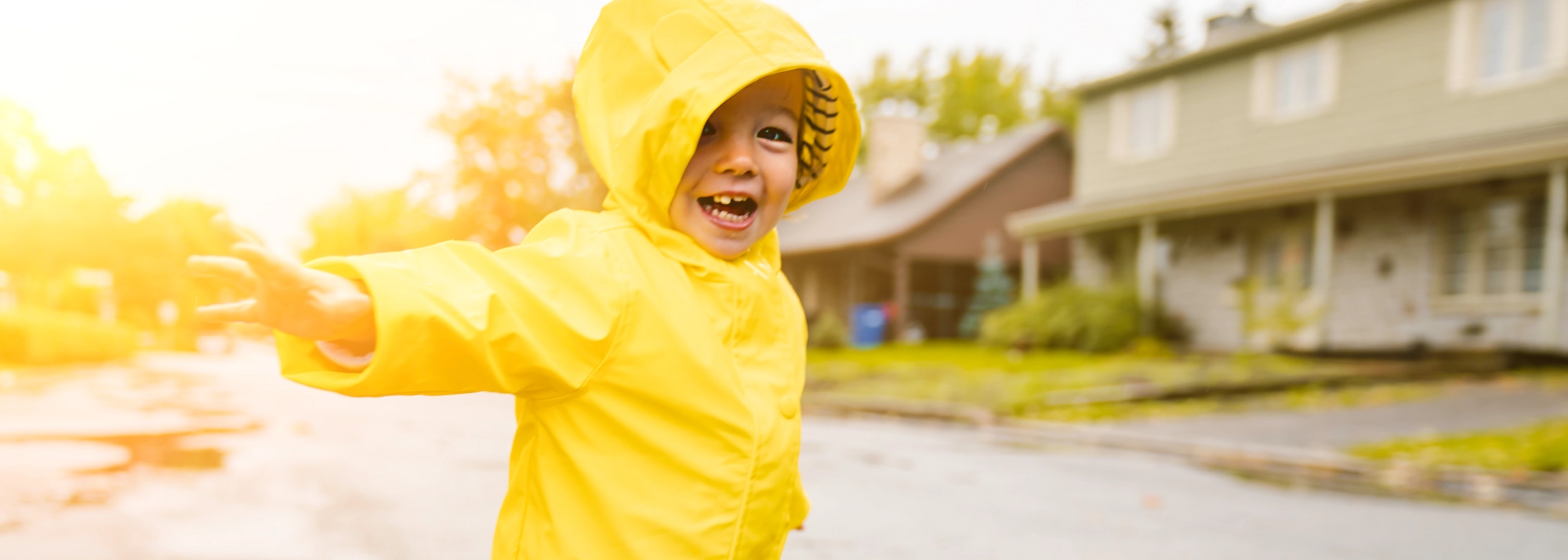 young_child_playing_in_raincoat_2000x714.webp