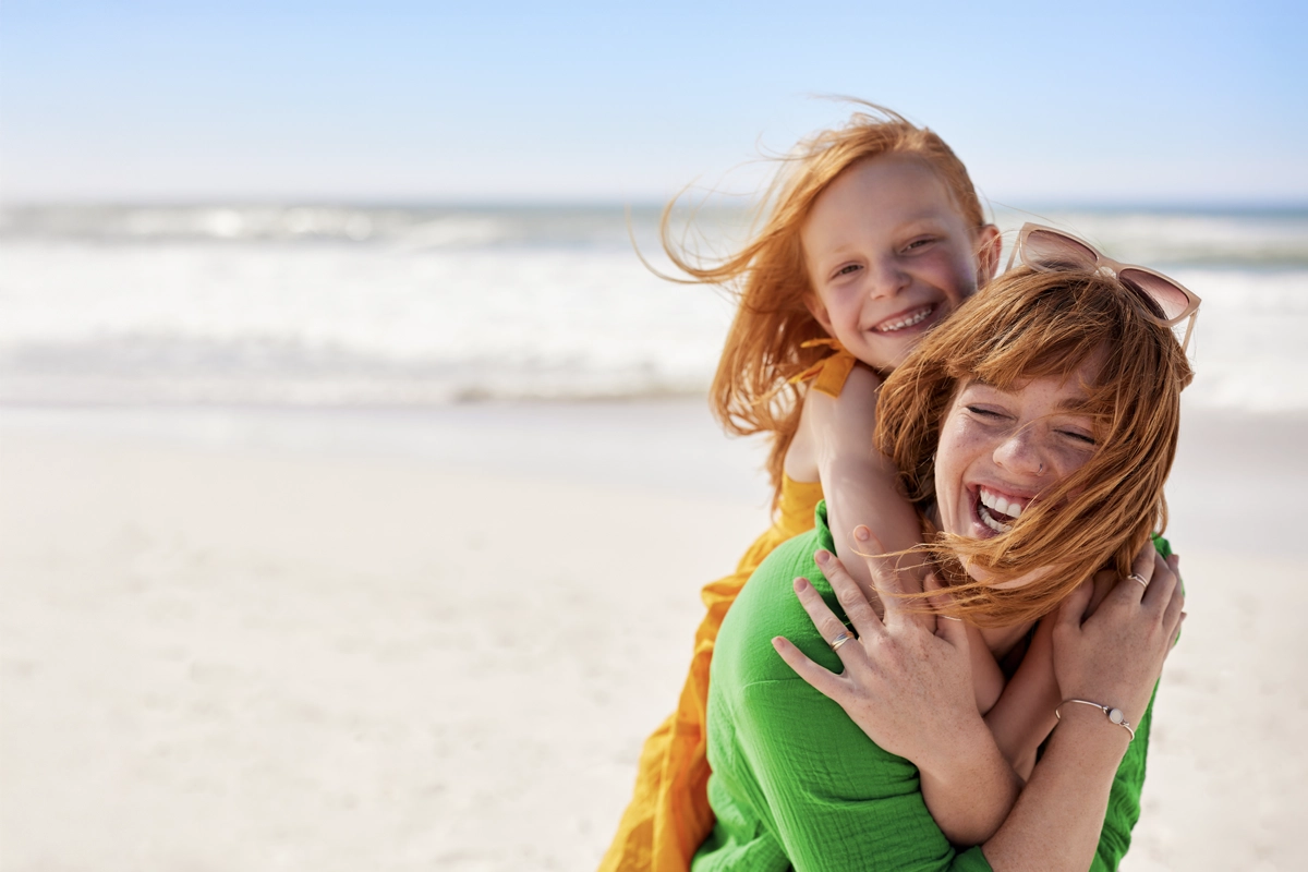 mother-daughter-smiling-beach-1200x800.webp