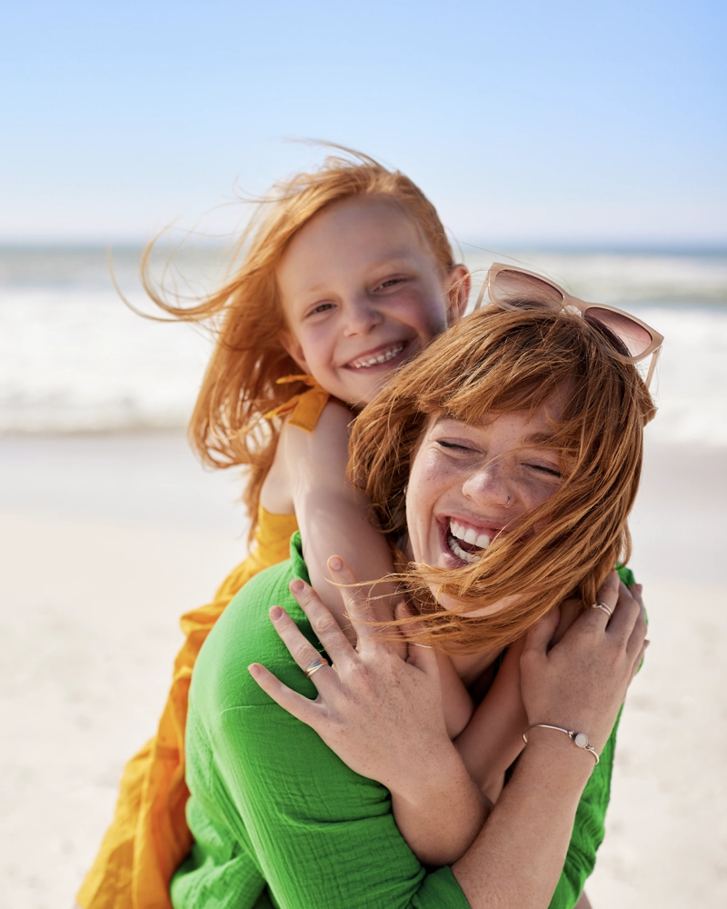 mother-daughter-smiling-beach-800x1000.webp